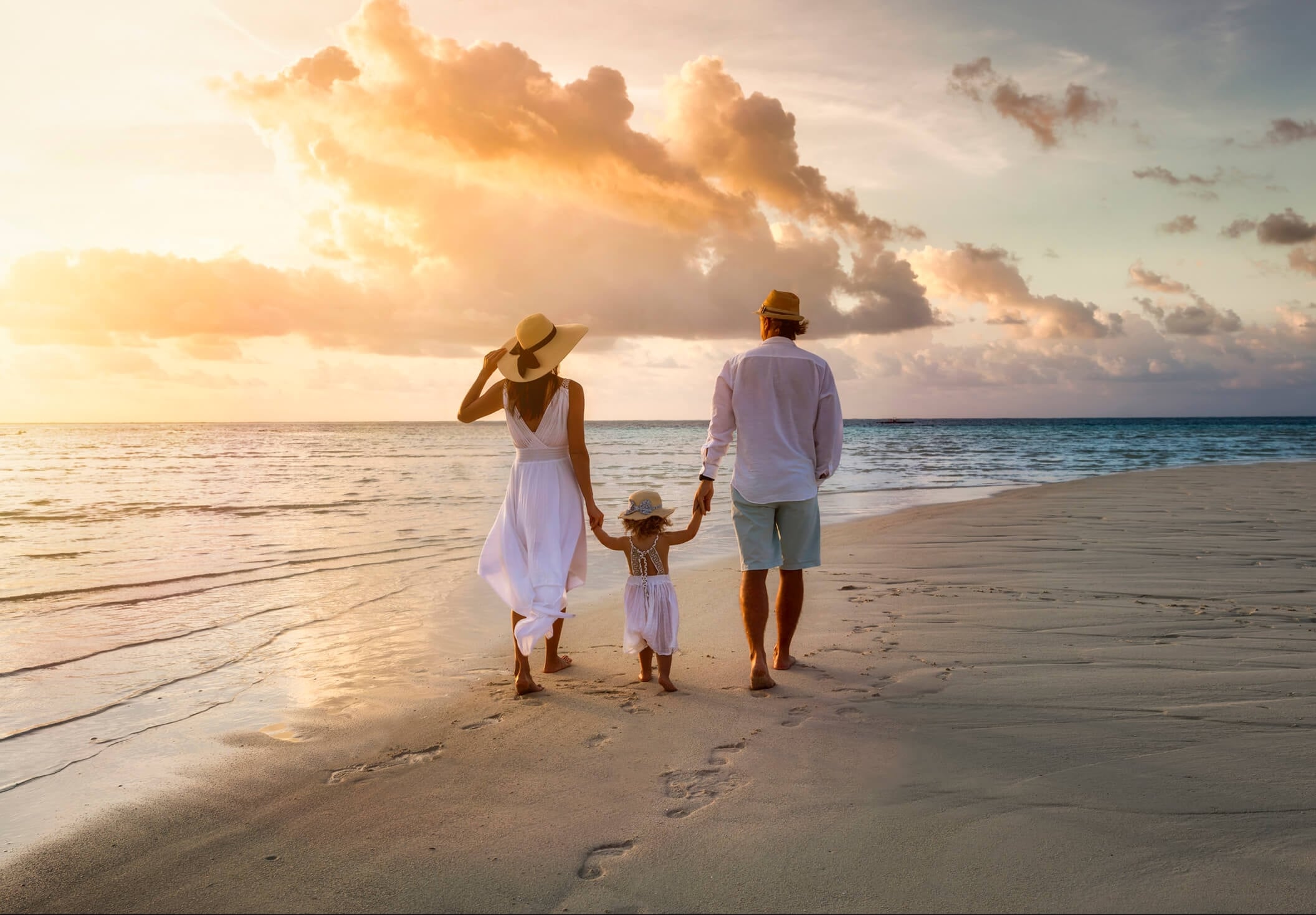 Family walking on beach at sunset